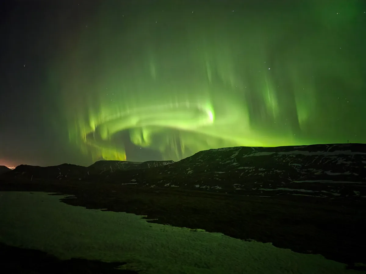 Northern Lights in Iceland - Green aurora dancing over snowy landscape